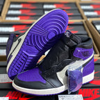 High-top sneaker angled side view with purple outsole, black upper, and purple heel panel