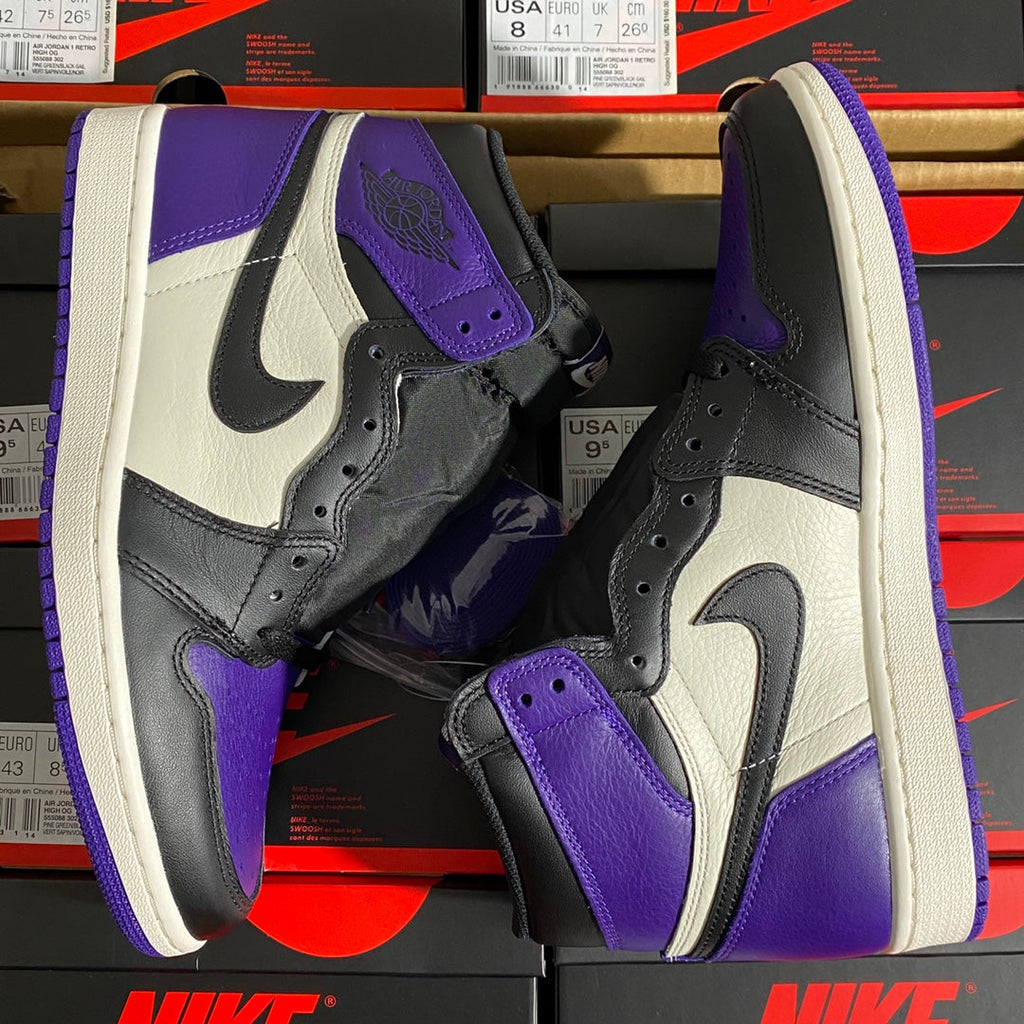 High-top sneaker pair close-up showing white Swoosh, black overlays, and purple accents