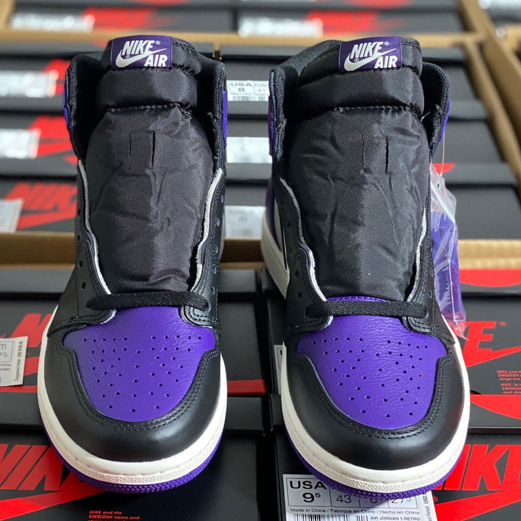 Back view of high-top sneakers with black padded collars, purple toe panels, and Nike Air tabs