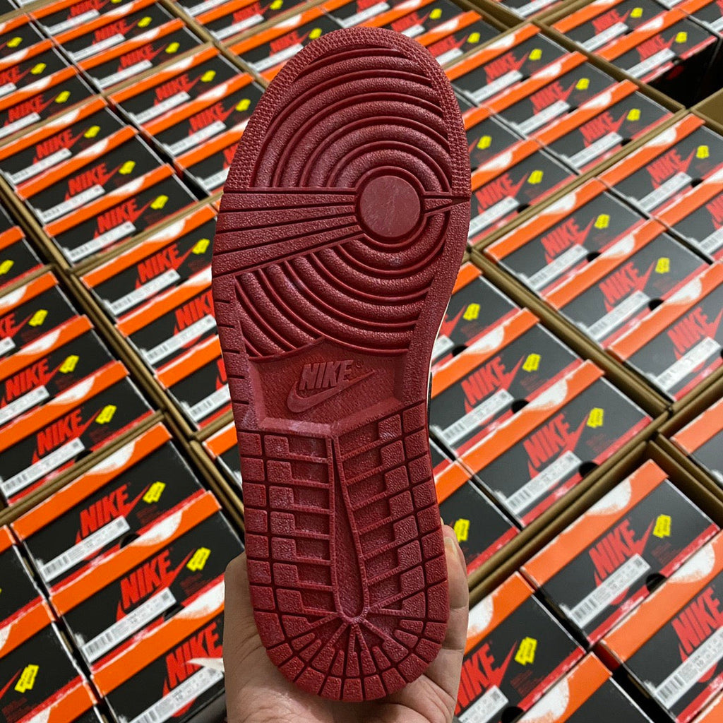 Shoe outsole with textured rubber tread in burgundy, viewed from the heel.