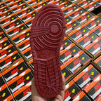 Shoe outsole with textured rubber tread in burgundy, viewed from the heel.