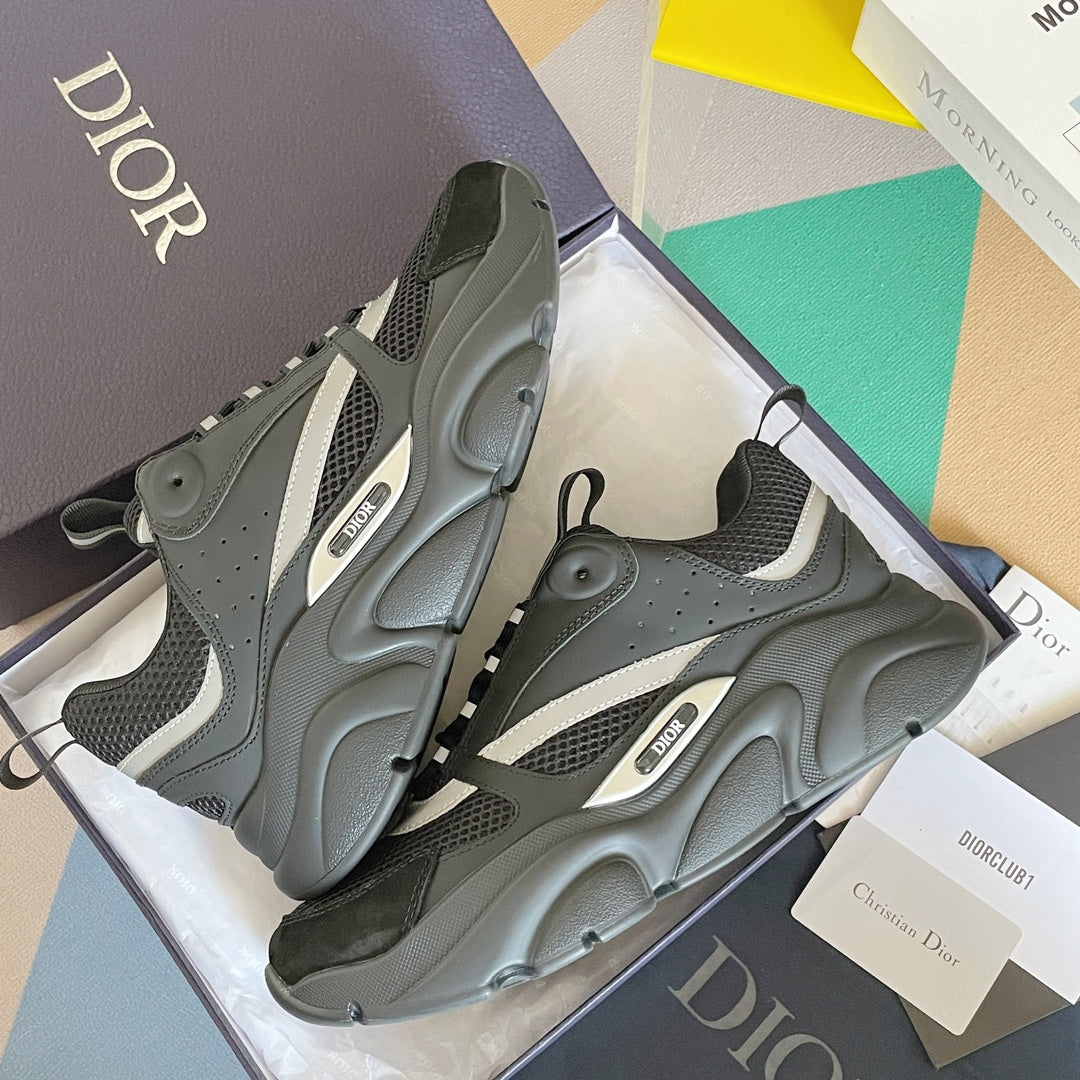 Gray sneakers with black mesh uppers and white stripe detailing, shown in a box.