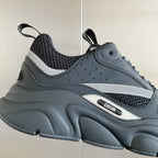 Front view of gray mesh sneakers with white stripe trim and DIOR badge detail.