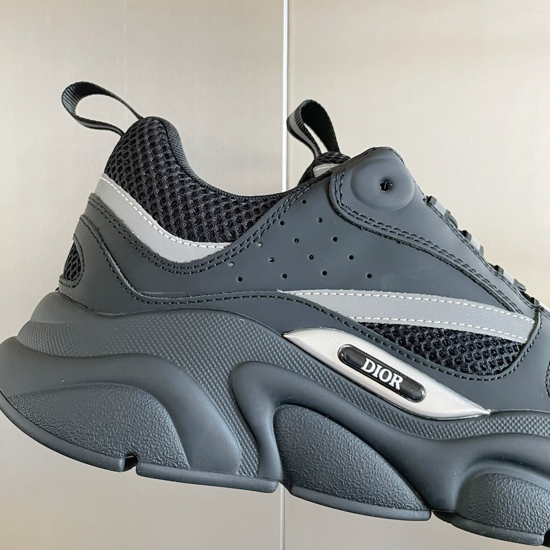 Front view of gray mesh sneakers with white stripe trim and DIOR badge detail.
