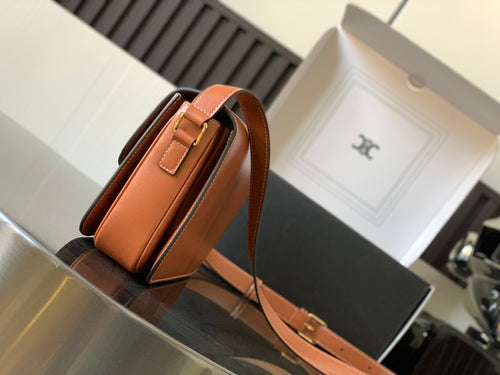 Celine bag in orange leather with gold clasp at top and curved shoulder strap