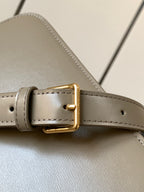 Celine bag strap close-up in beige leather with gold-tone buckle and stitched edges