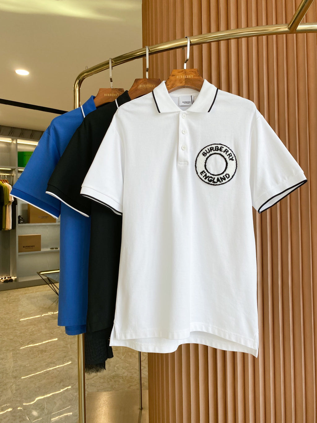 White polo shirt with black-trim collar and Burberry England logo patch on chest