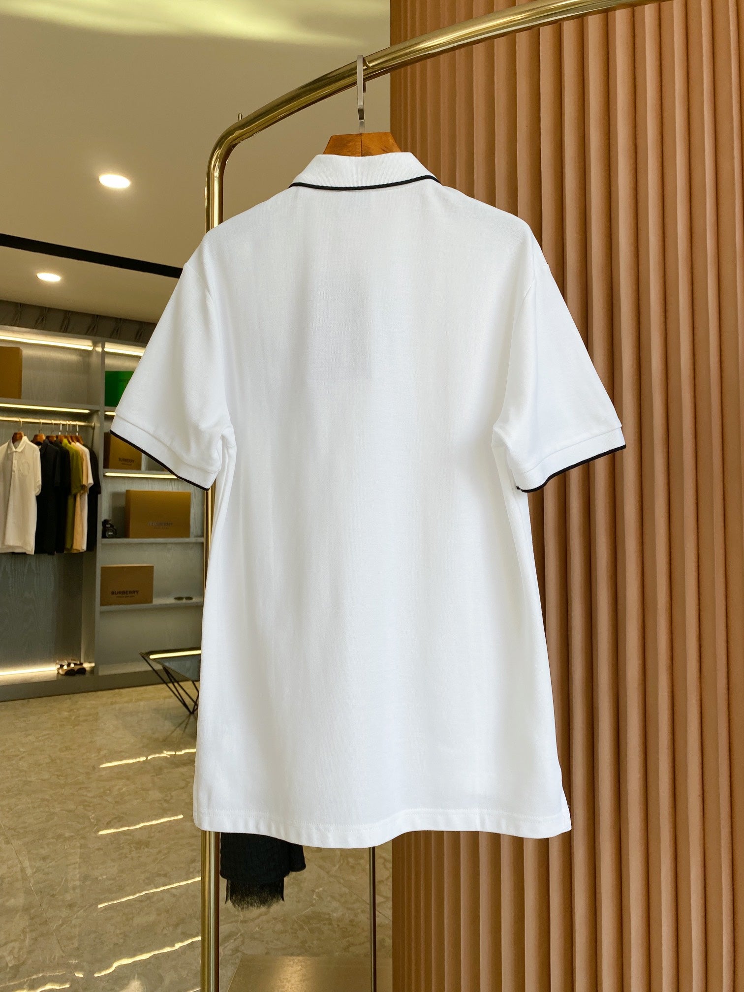 White polo shirt with black-trim collar, shown from the back