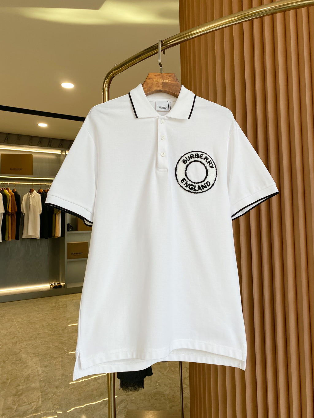 White polo shirt with black-trim collar and Burberry England logo patch on chest