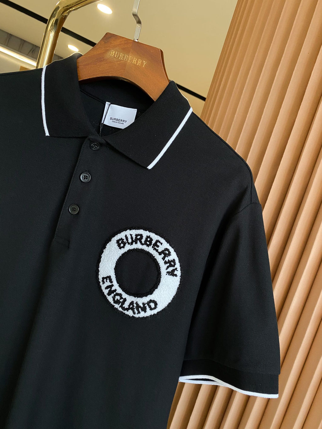 Black polo shirt close-up with white-trimmed collar and circular chest logo patch
