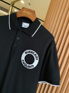 Black polo shirt close-up with white-trimmed collar and circular chest logo patch