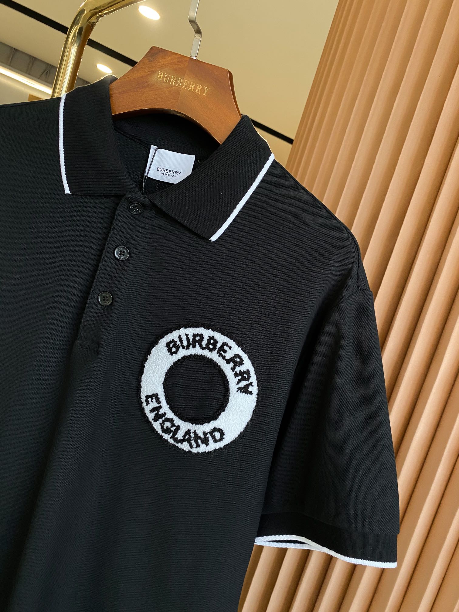 Black polo shirt close-up with white-trimmed collar and circular chest logo patch