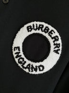 Circular logo patch on black polo shirt with white embroidered text