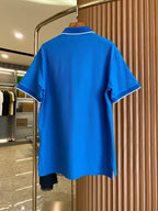 Back view of blue polo shirt with short sleeves, hanging on a rack