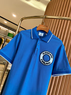 Blue polo shirt on a hanger with white-trim collar and Burberry England logo patch