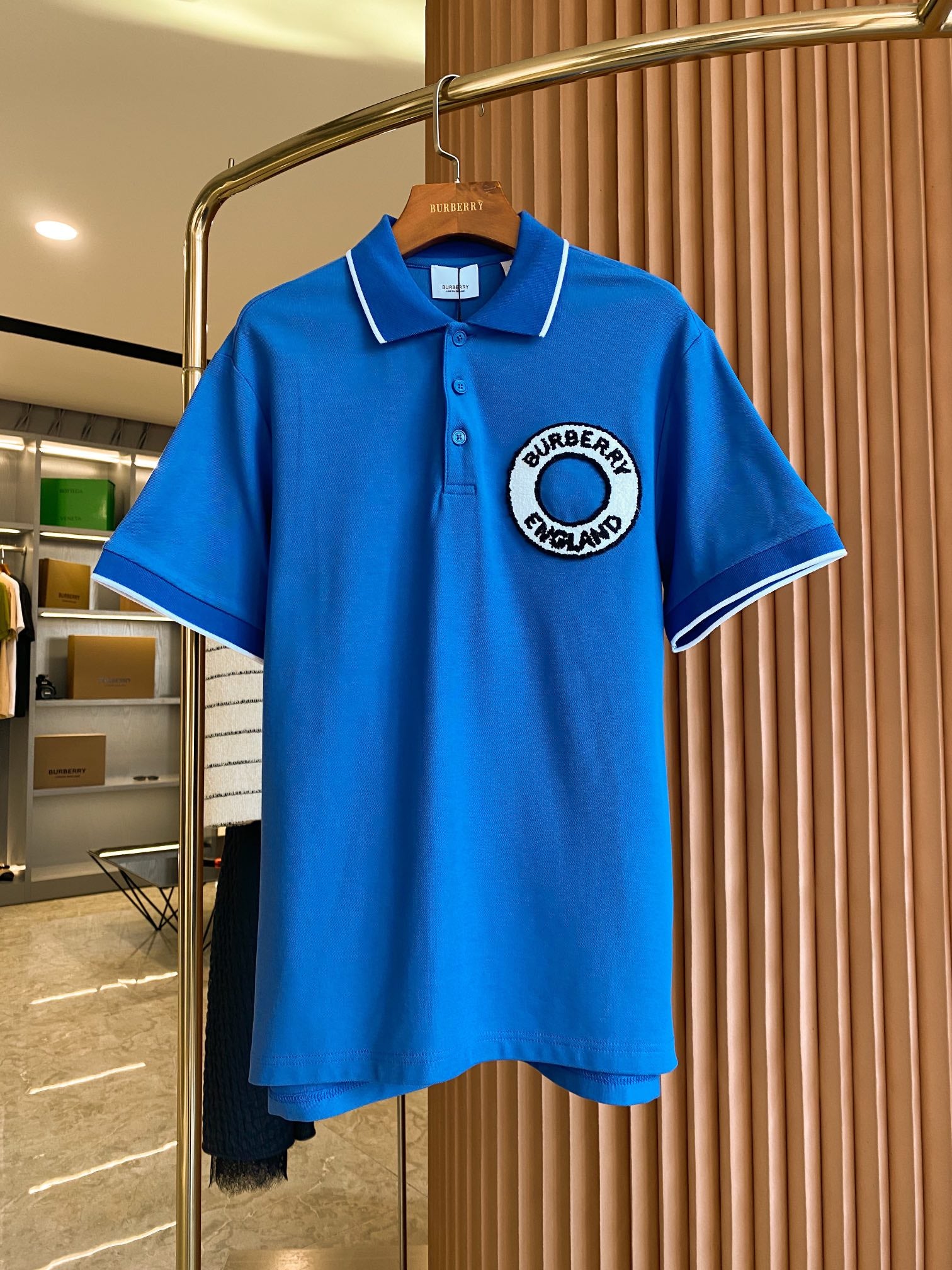 Blue polo shirt with white-trim collar and short sleeves, featuring a Burberry logo patch