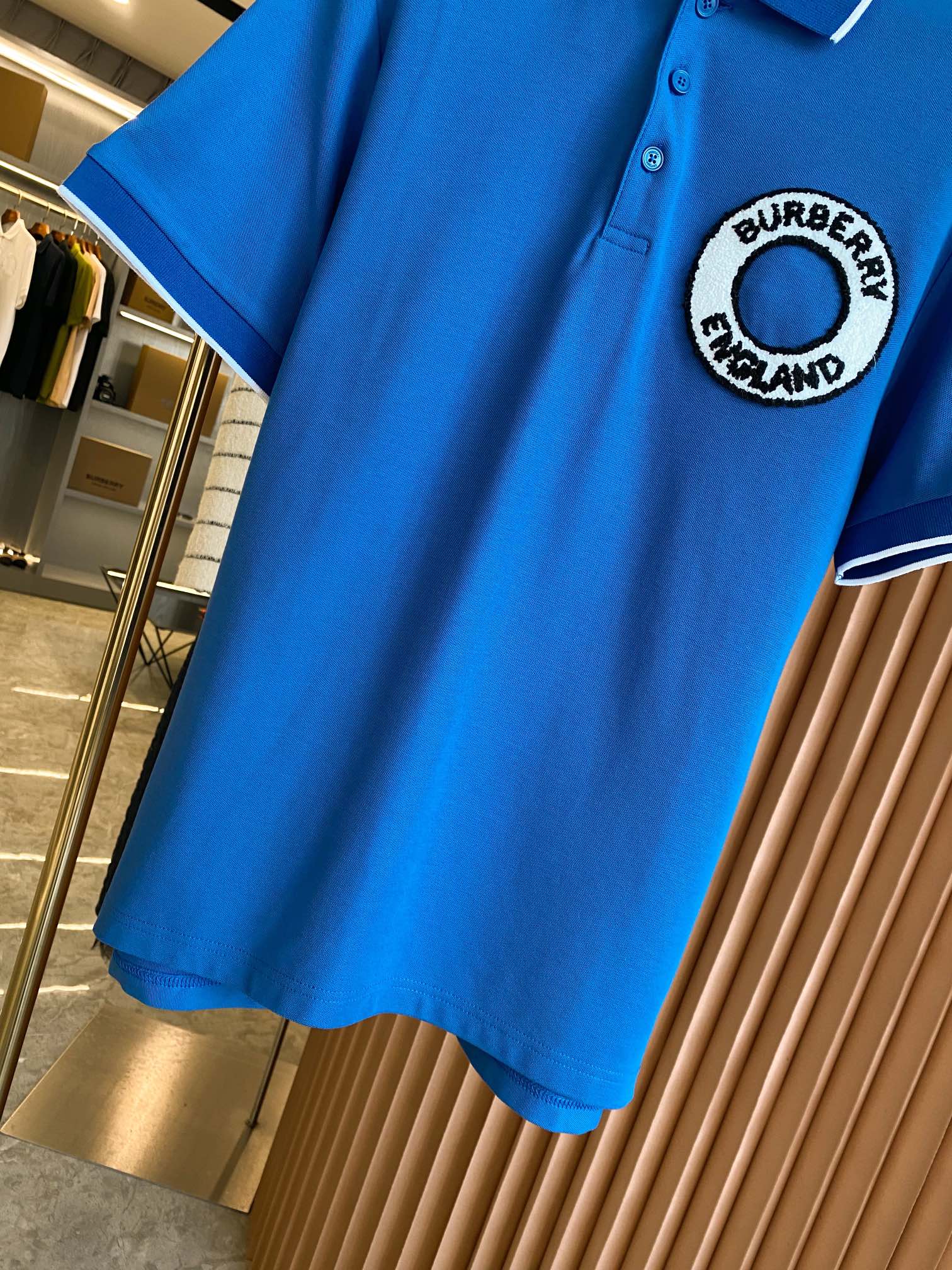 Blue polo shirt with Burberry England round logo patch on the chest