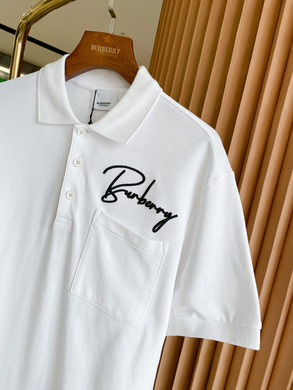 White Burberry polo shirt close-up of chest pocket and script logo