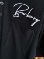 Black polo shirt pocket with white Burberry logo embroidery and button placket