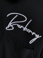 Close-up of black polo shirt with white Burberry logo embroidery and buttons