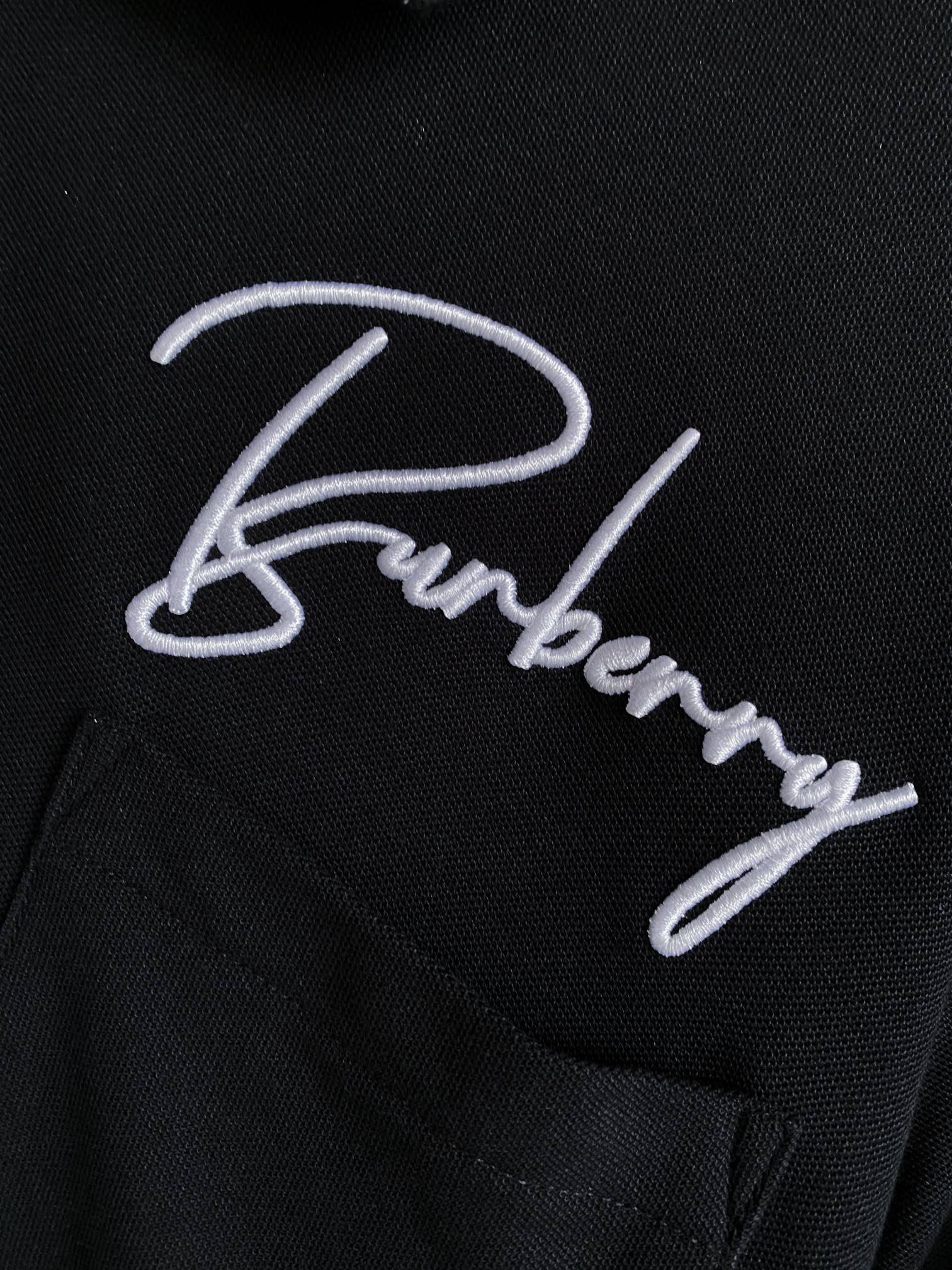 Close-up of black polo shirt with white Burberry logo embroidery and buttons