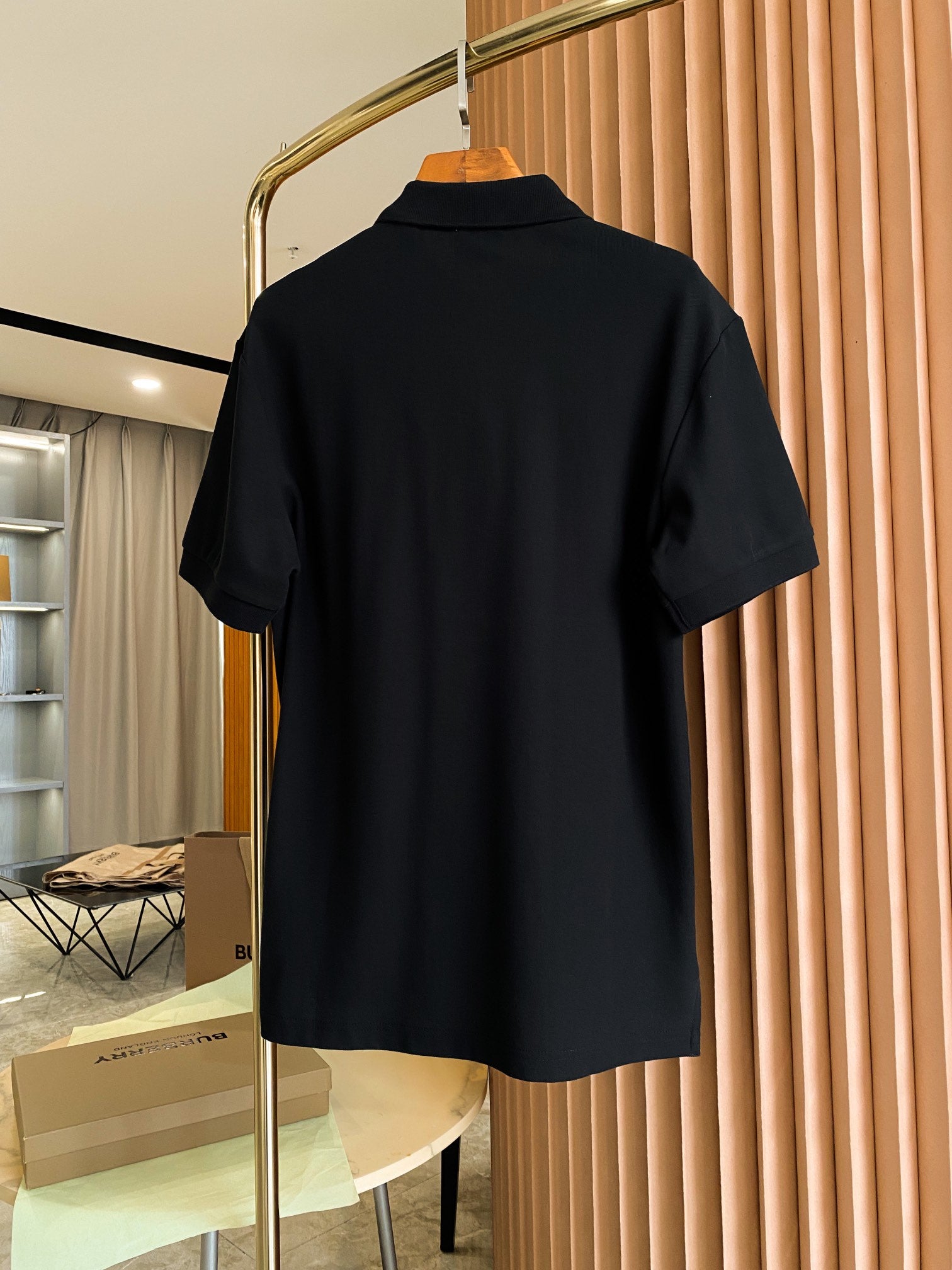 Back view of Burberry black short-sleeve polo shirt on a hanger