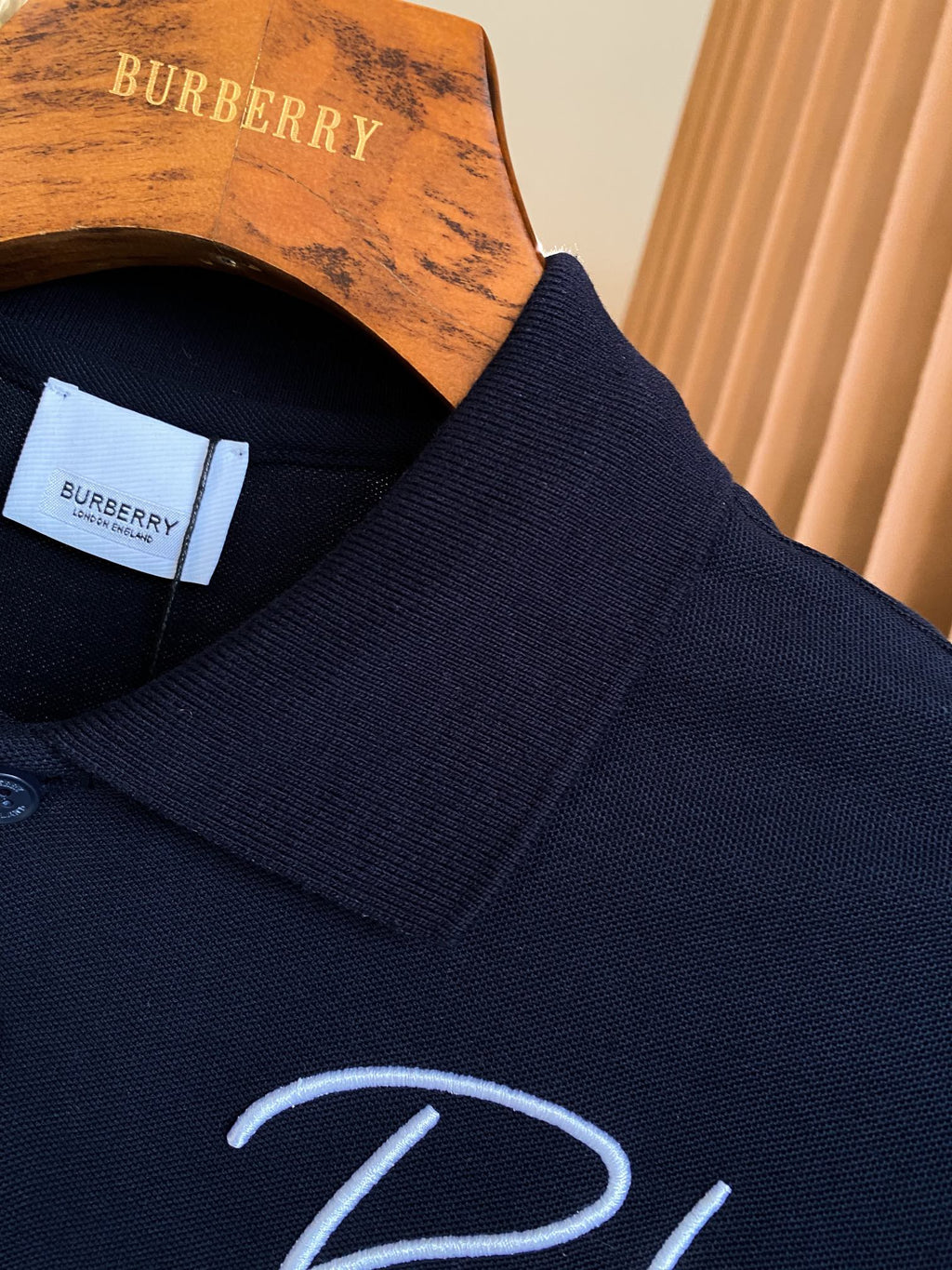 Burberry polo shirt collar detail in dark navy with ribbed trim, partial logo embroidery