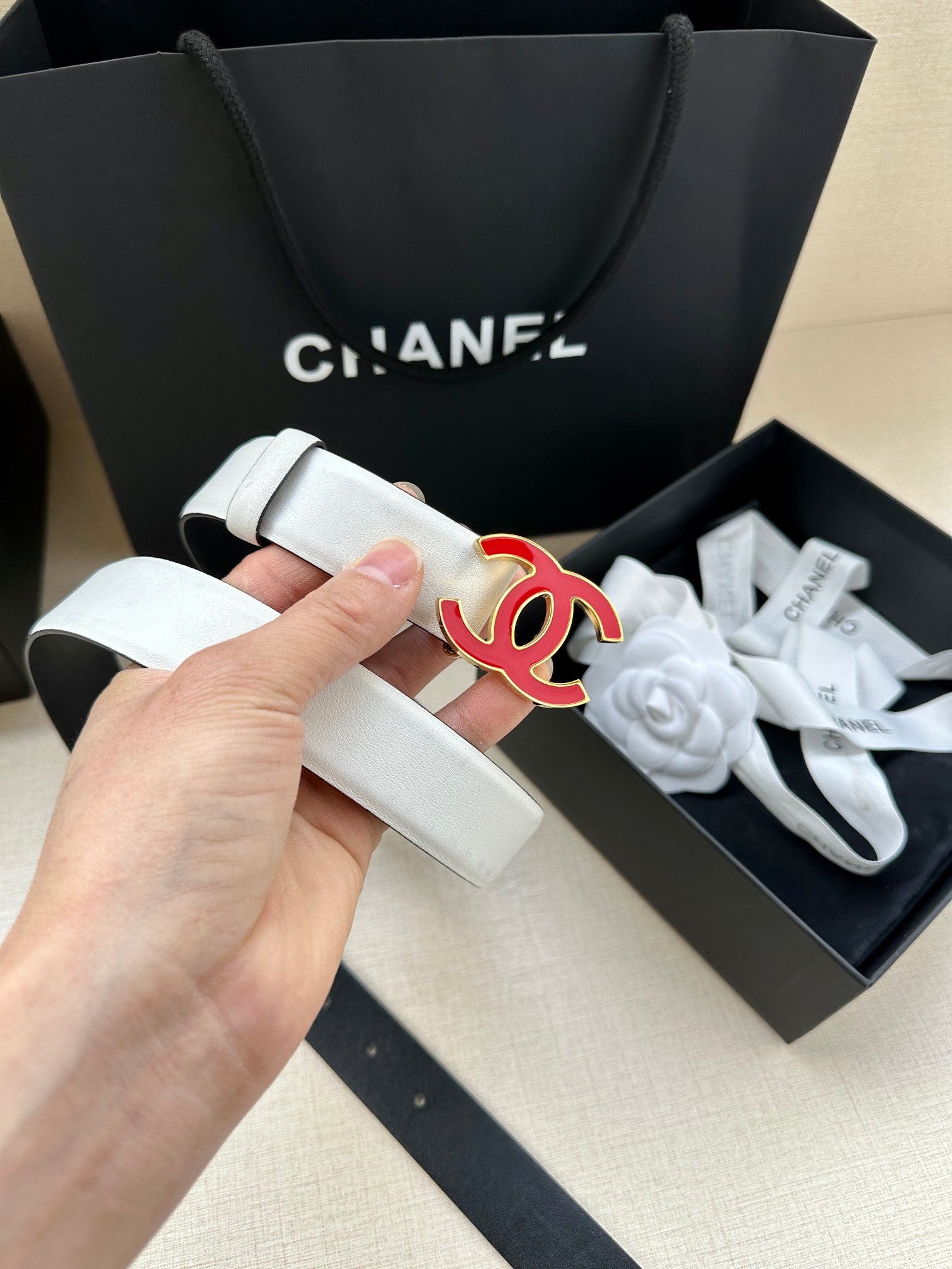 Leather belt with Chanel logo buckle, light cream strap held in hand