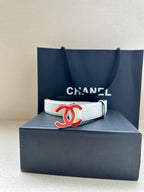 Leather belt with Chanel logo buckle on box, light cream strap with silver-tone holes