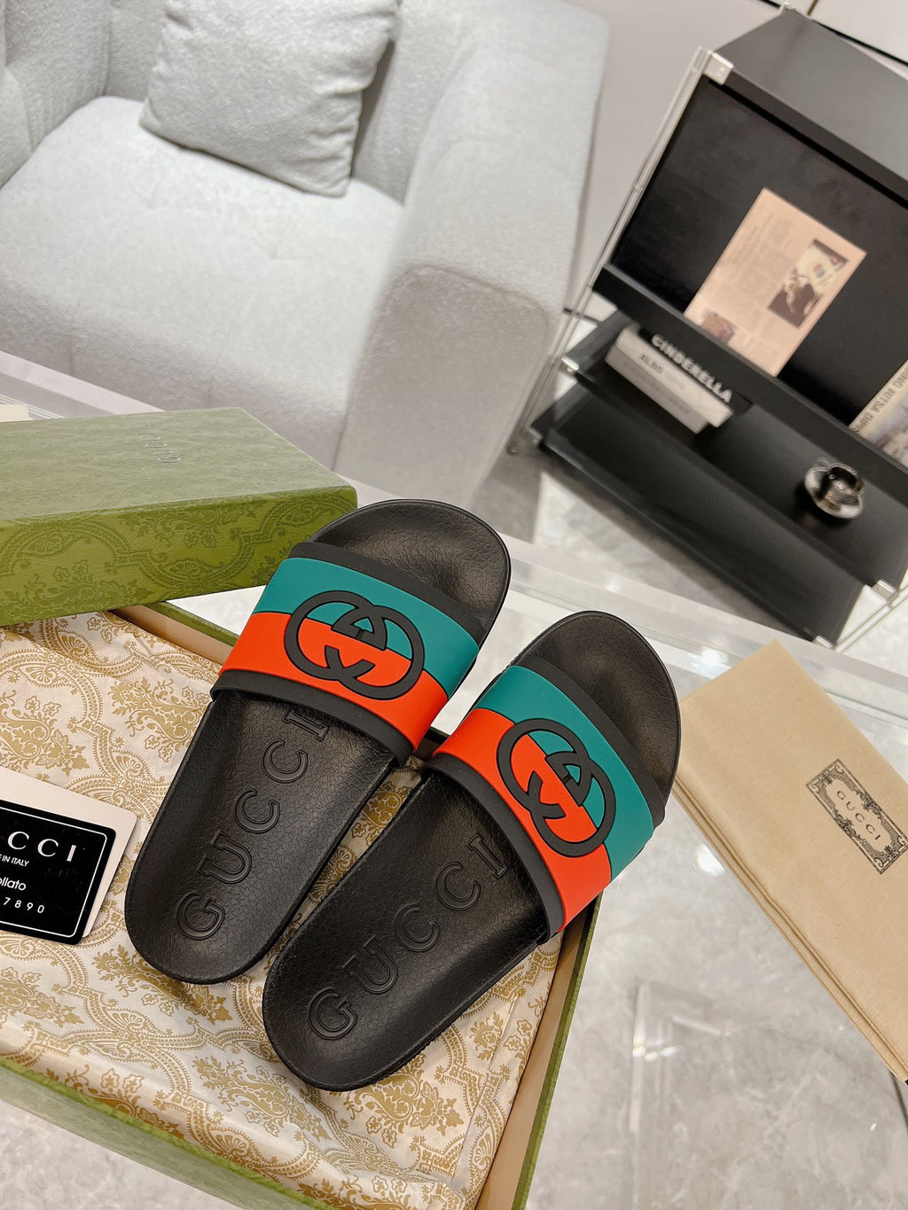 Black Gucci slide sandals with embossed logo soles and orange/teal strap