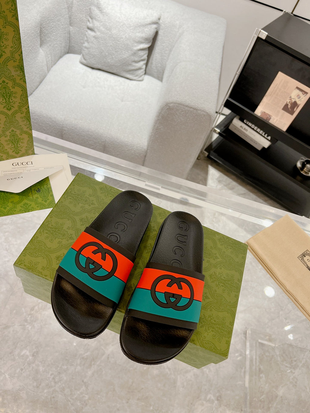 Black Gucci slide sandals with embossed logo footbeds and orange/teal band