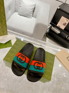 Black Gucci slide sandals with embossed logo footbeds and orange/teal band