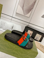Black Gucci slide sandals with colorful orange and teal logo strap