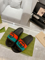 Pair of black Gucci slide sandals with embossed footbeds and orange/teal bands