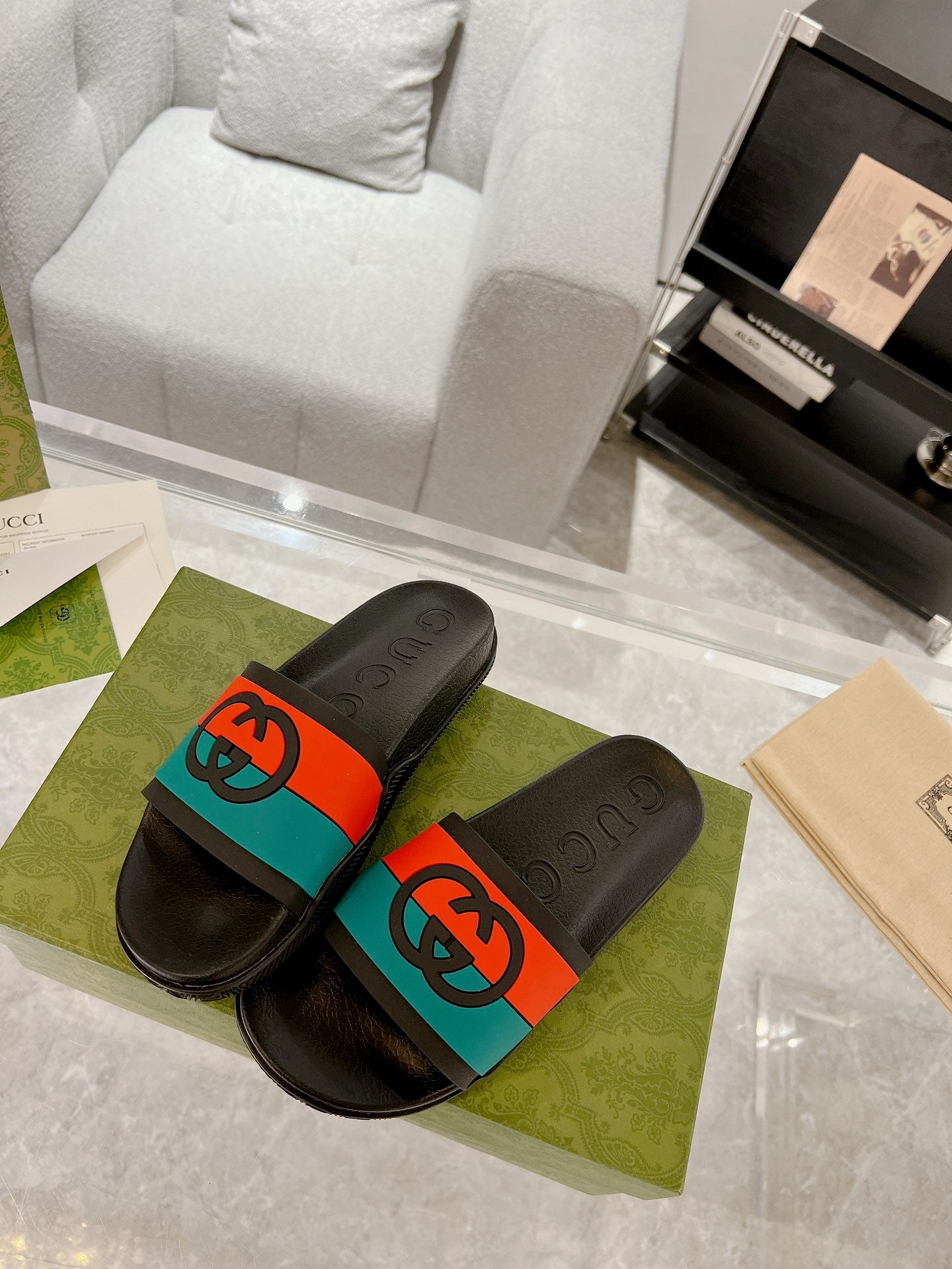 Pair of black Gucci slide sandals with embossed footbeds and orange/teal bands
