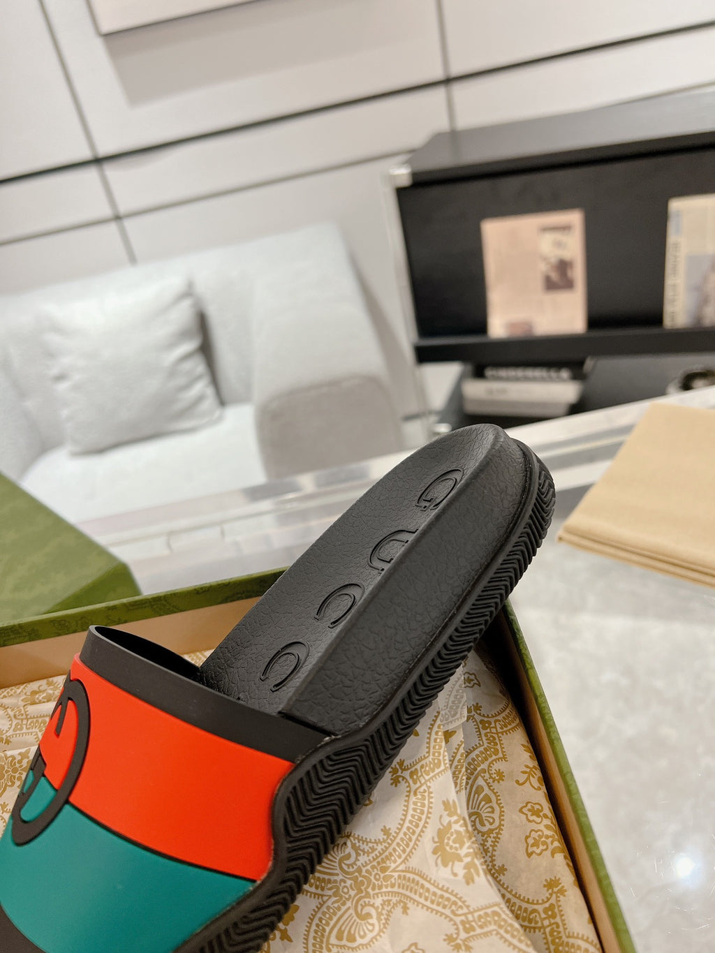 Black Gucci slide sandal with embossed footbed and orange/teal logo band