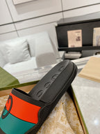 Black Gucci slide sandal with embossed footbed and orange/teal logo band