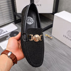 Versace black glitter loafer with gold buckle and crest emblem, held in hand