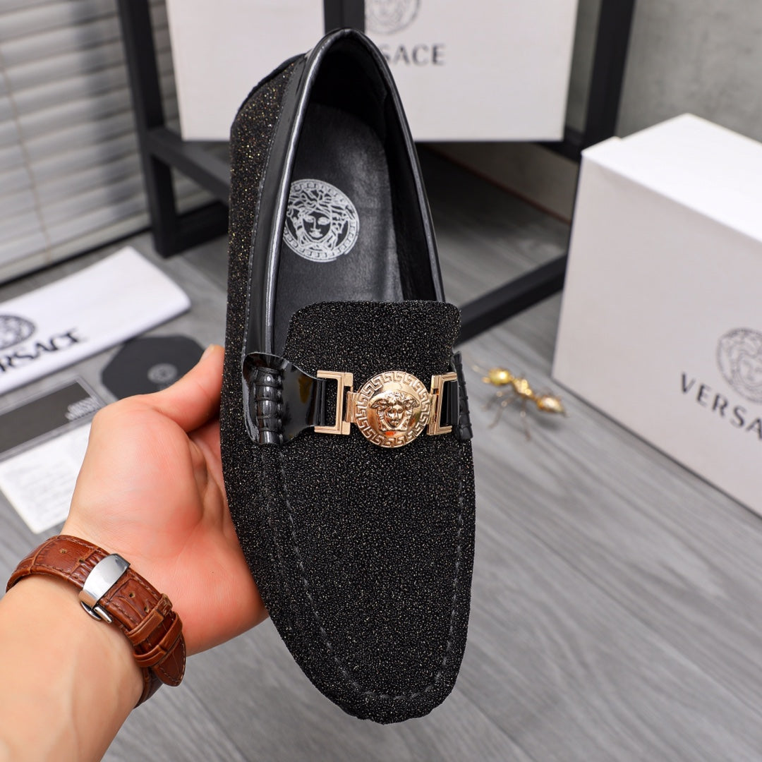 Versace black glitter loafer with gold buckle and crest emblem, held in hand