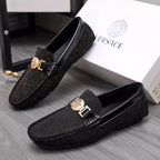 Versace black glitter loafers with gold buckle and crest emblem, angled pair