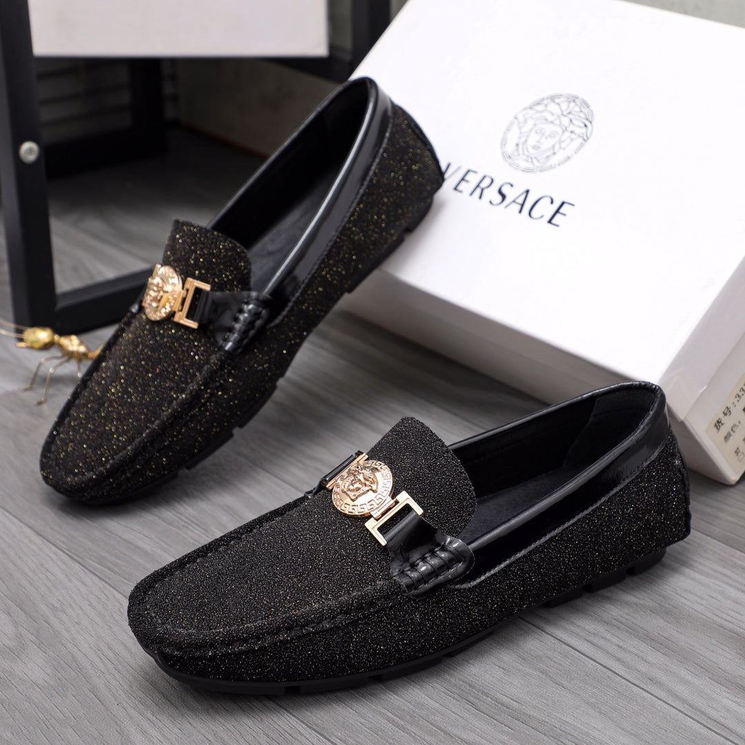 Versace black glitter loafers with gold buckle and crest emblem, angled pair