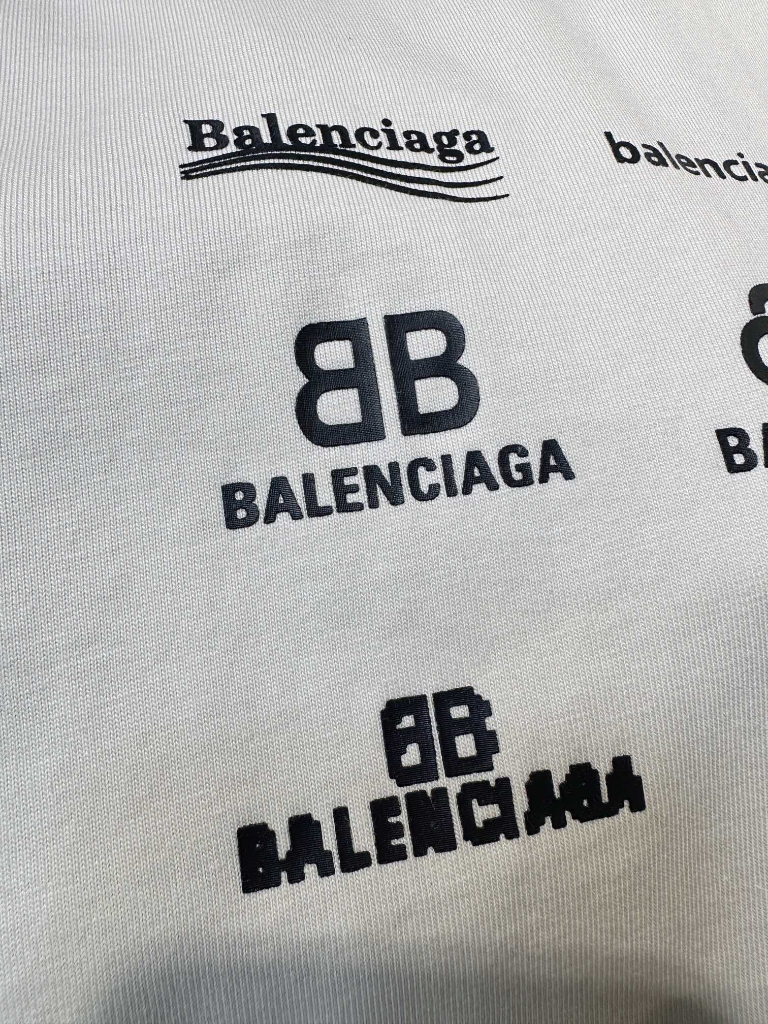 White T-shirt fabric close-up with black Balenciaga wordmark and 8B logos