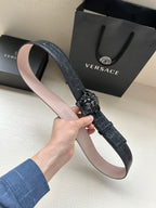 Black leather belt with croc texture and dark Medusa buckle detail, shown flat.