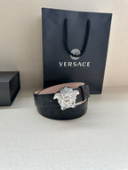 Black leather belt with croc texture and silver-tone Medusa buckle on display.