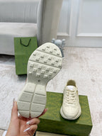 Gucci unisex sneaker outsole toe view with tread, with matching lace-up pair on box