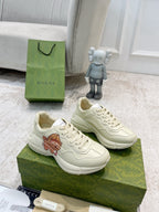Gucci unisex white sneakers with bear graphic, lace-up, side view on green box