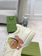 Gucci unisex white sneaker close-up with embroidered bear graphic and lace-up panel