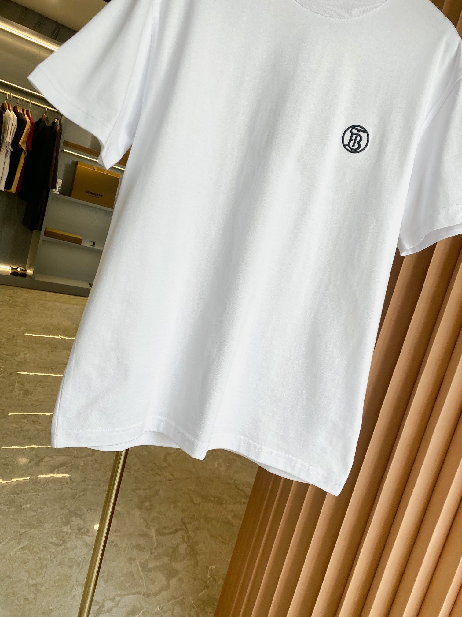 White short-sleeve crewneck T-shirt, angled view showing front hem and logo.