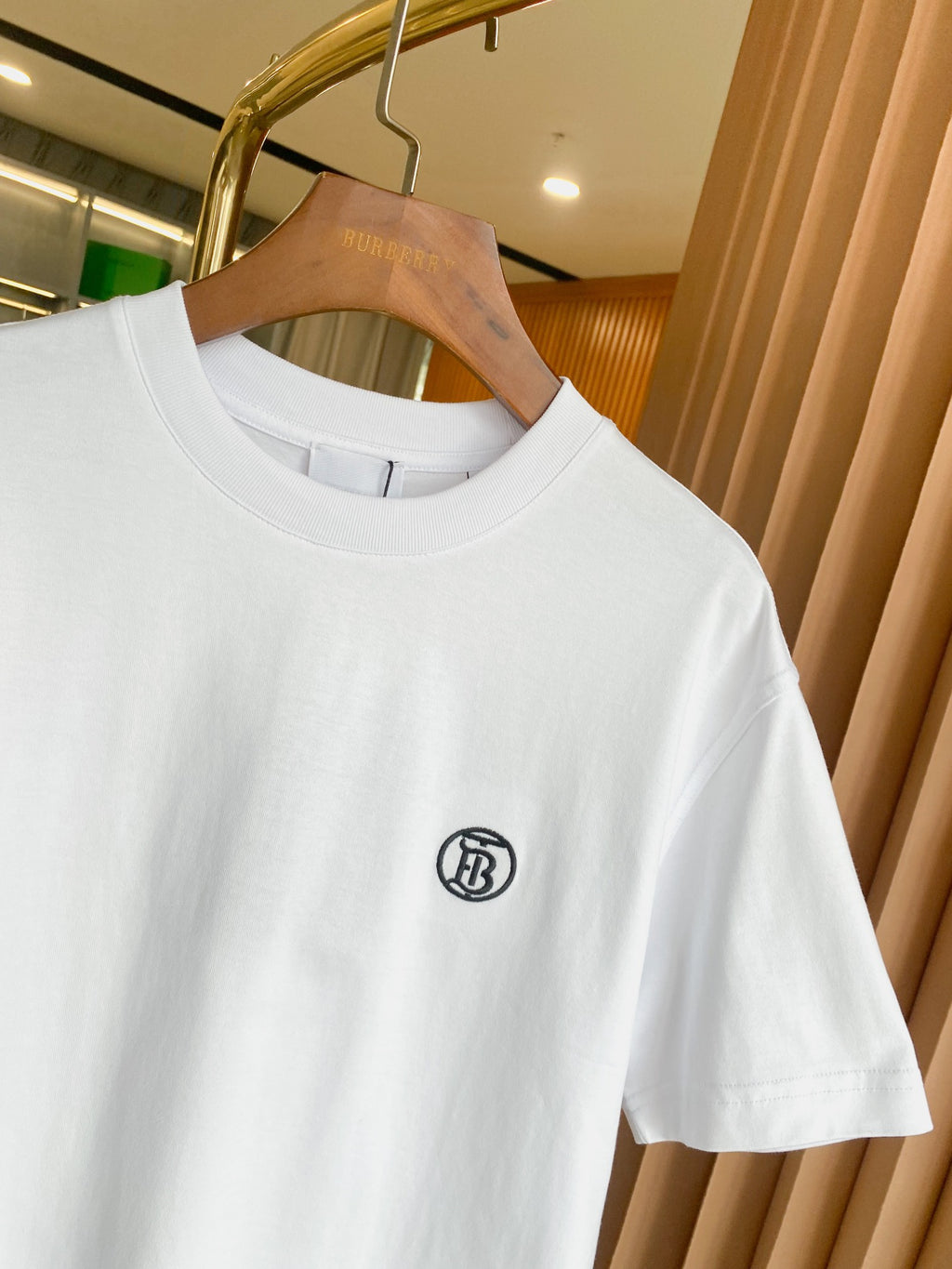 White crewneck T-shirt with short sleeves and small black chest logo near collar.