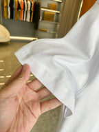 White short-sleeve T-shirt held by hand, showing soft fabric and sleeve hem.